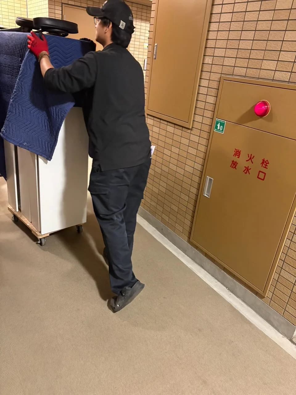 保護マットをかけた大型品を台車で運ぶスタッフ