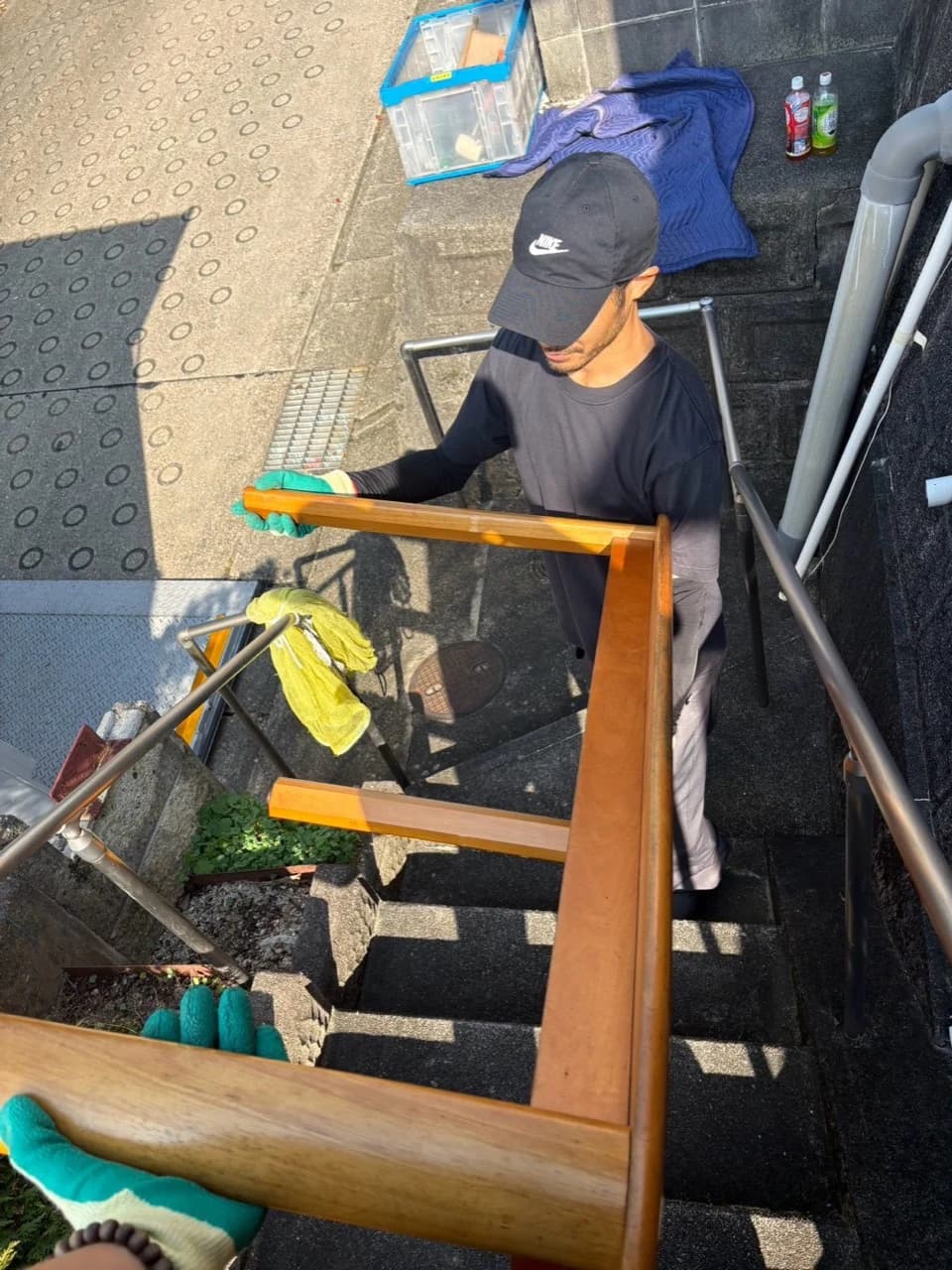 木製家具を屋外の階段で運ぶスタッフ