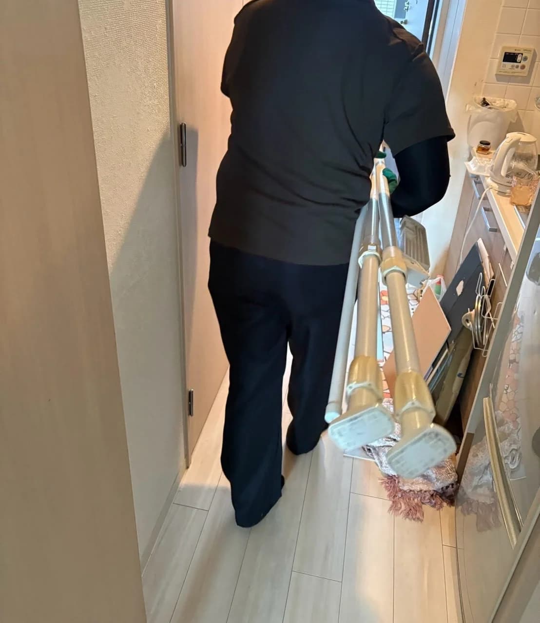 長い棒状の品物を通路で運んでいる様子