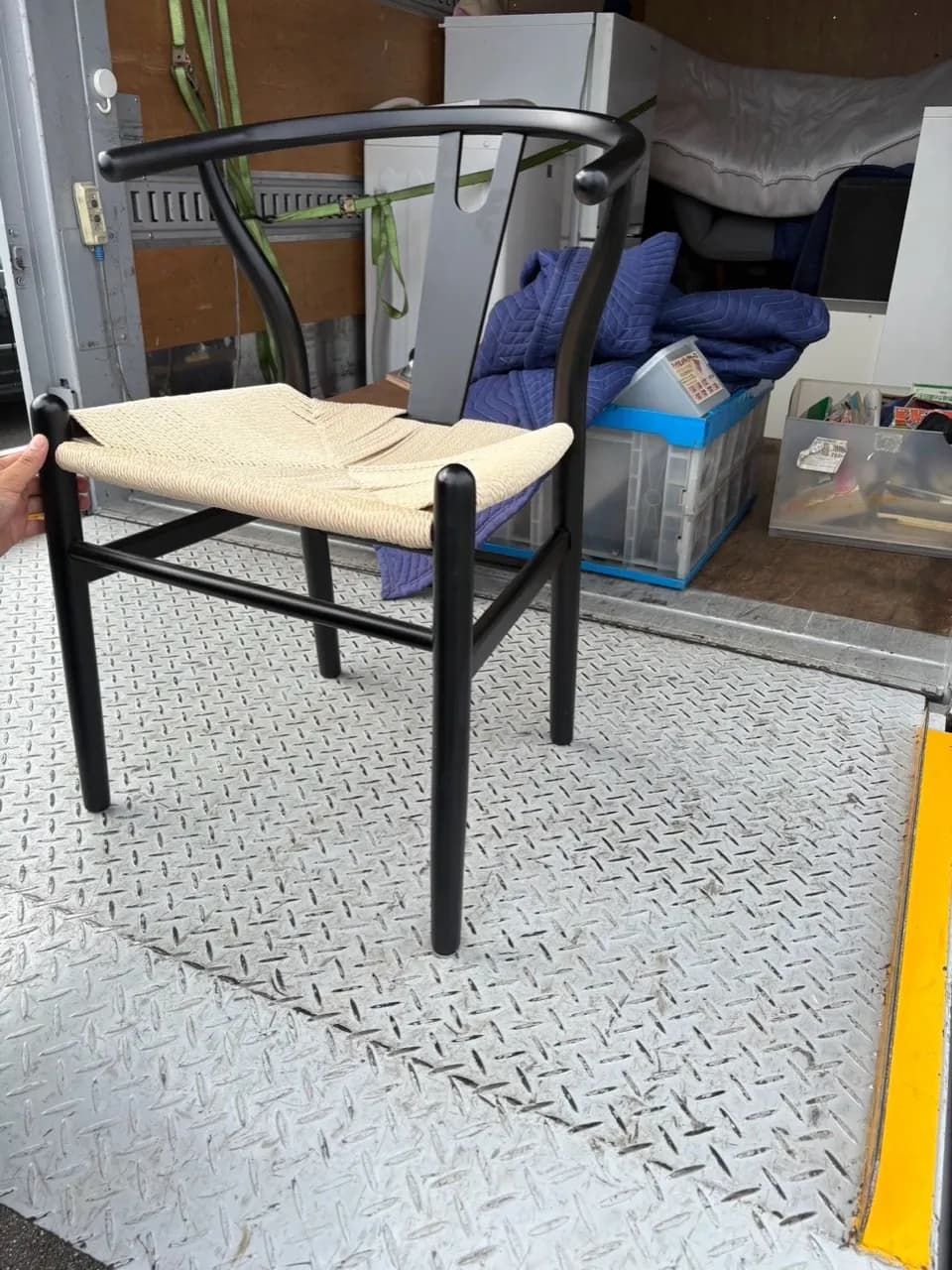トラックの荷台の手前で持ち上げられた黒い椅子の全体