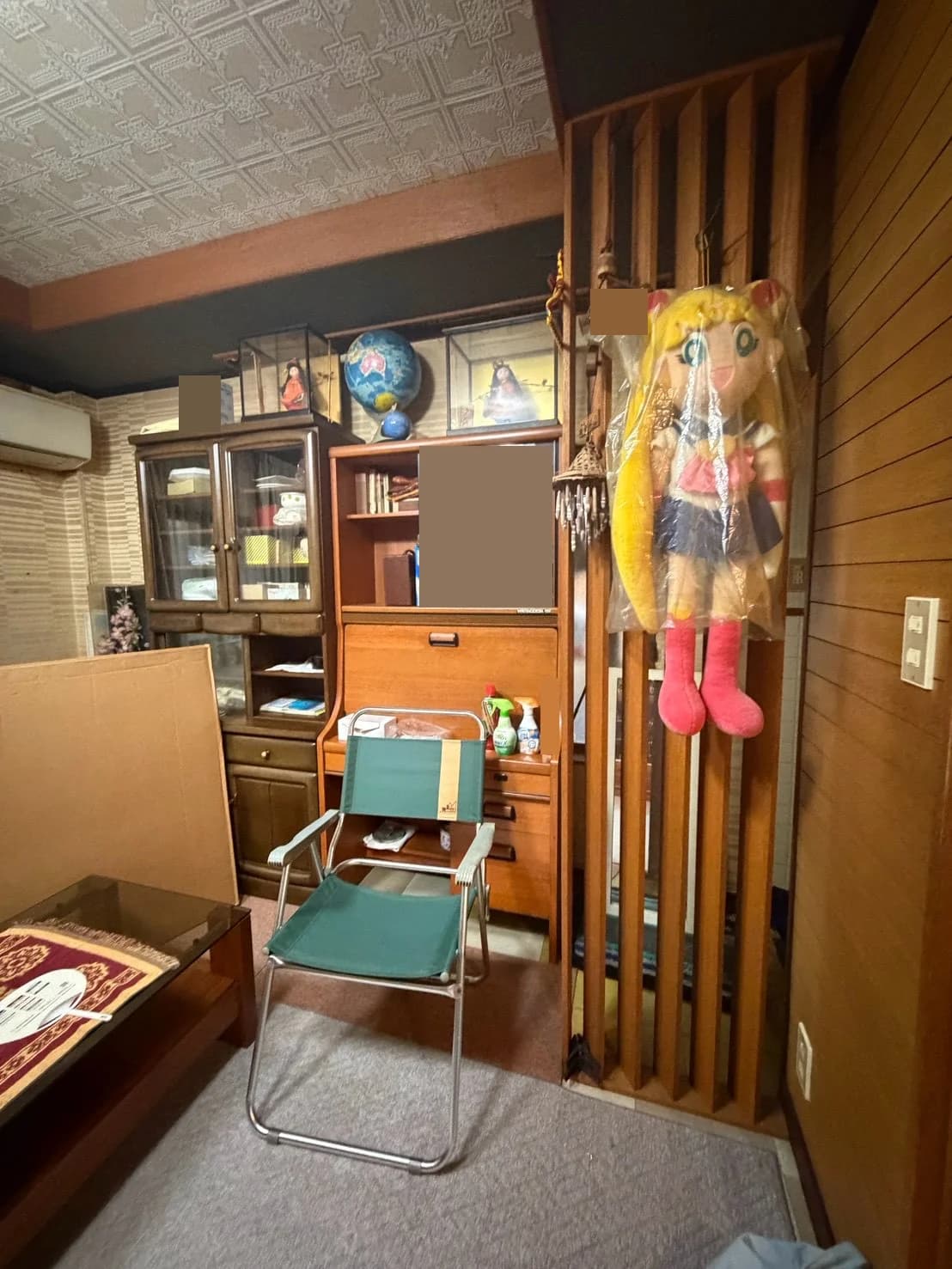 収納家具、折りたたみ椅子、人形などが置かれた室内