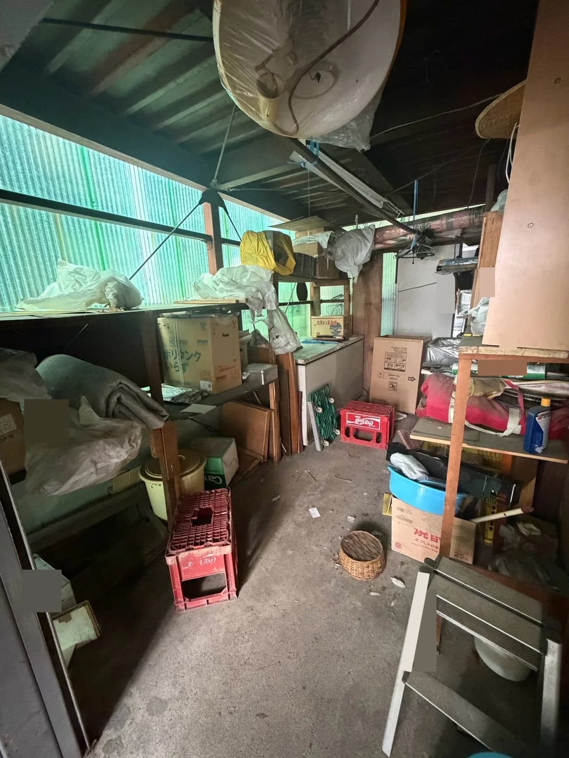 家具や箱、寝具、脚立などが置かれた保管スペースの全景