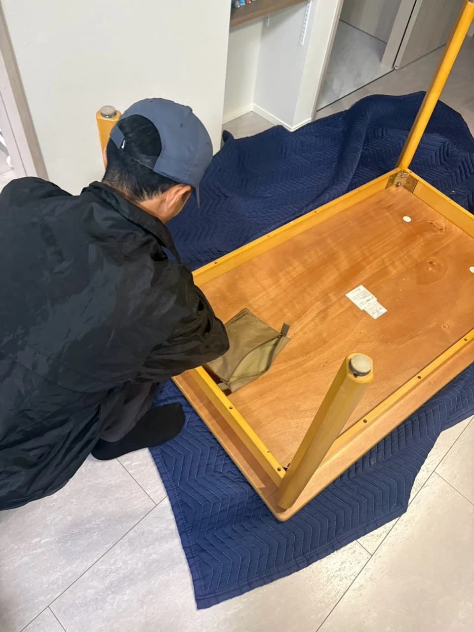 養生マットの上でダイニングテーブルの搬出準備をするスタッフ