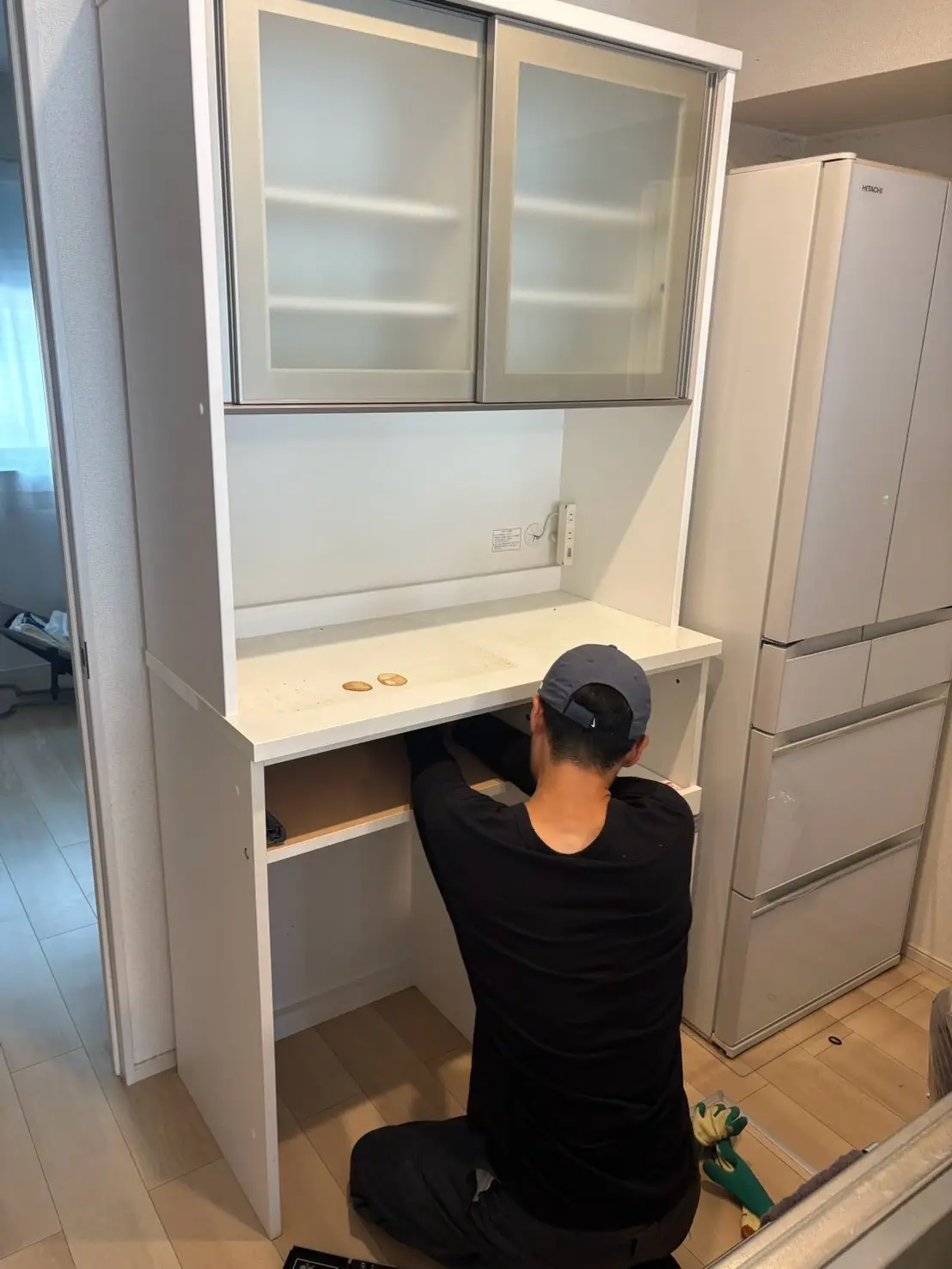 食器棚の下段を確認するスタッフ。隣に冷蔵庫