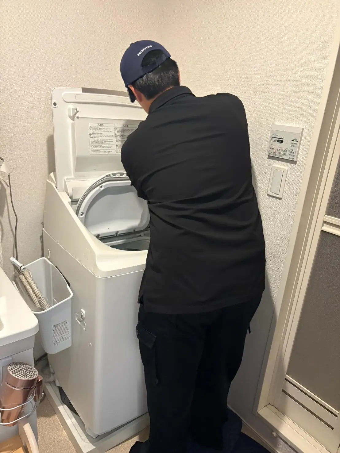 洗面所で洗濯機を確認するスタッフ
