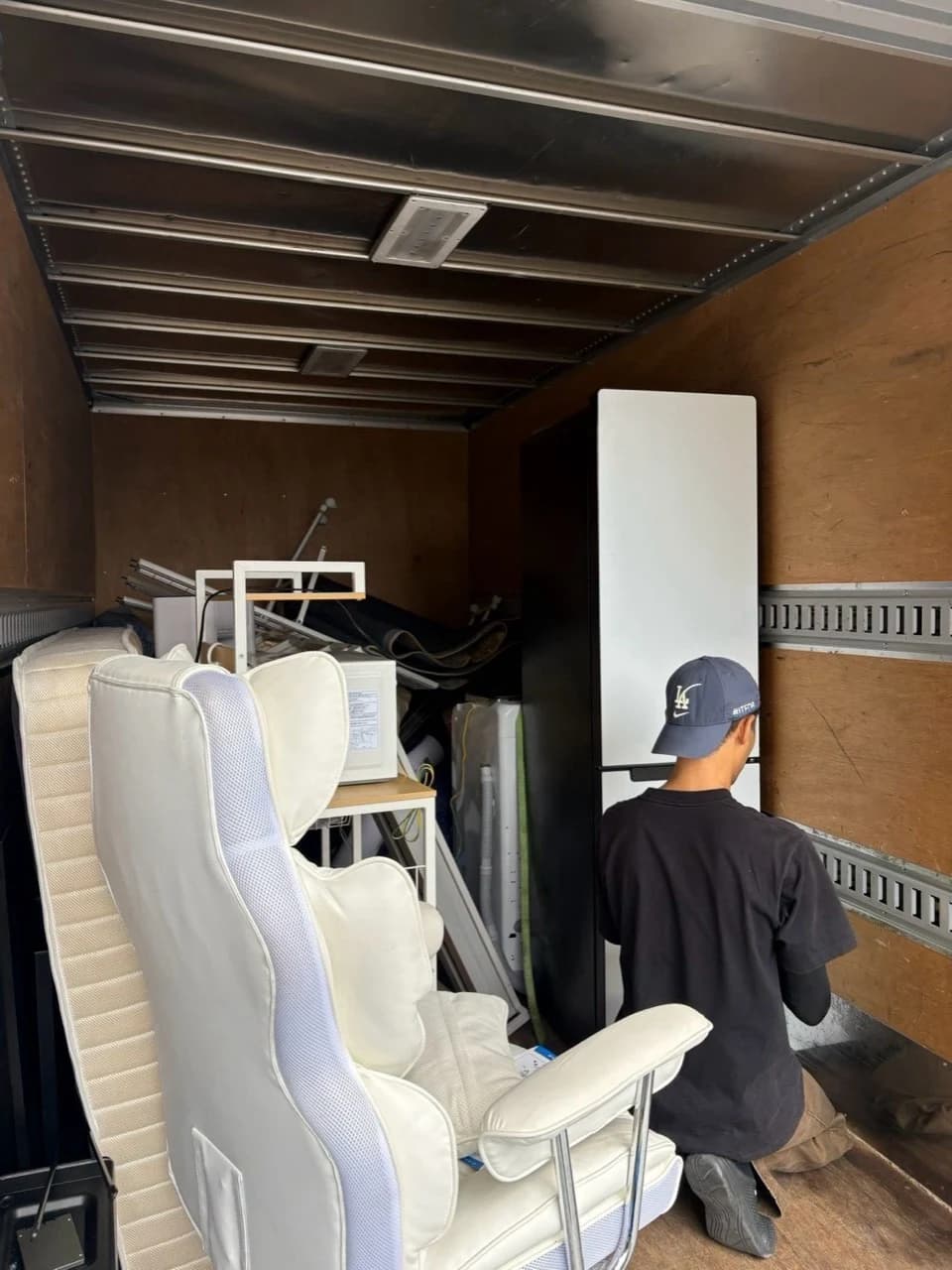 荷台で冷蔵庫の固定作業をするスタッフ