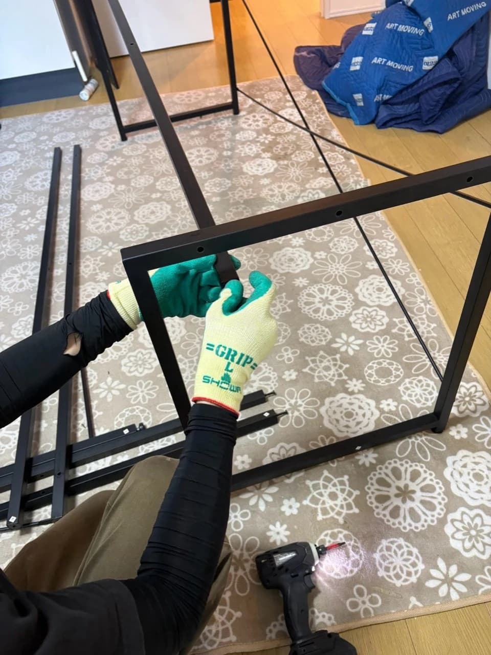 室内で黒い金属フレームの接合部分を外す作業