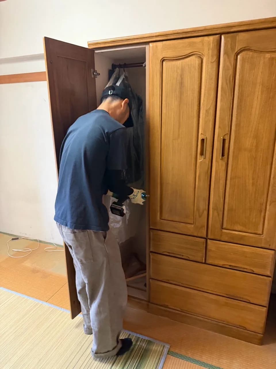 工具を使って大型の木製収納家具を扱うスタッフ