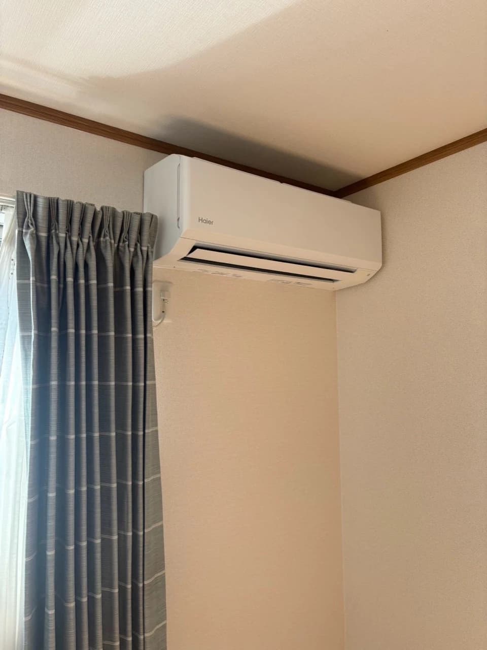 カーテンのそばに設置されたエアコンの室内機