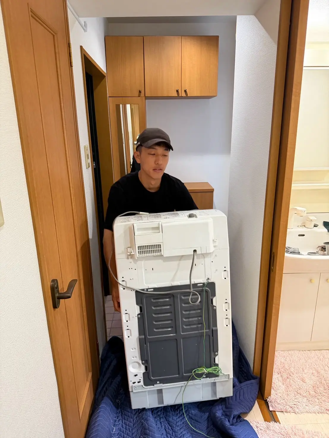洗面所から洗濯機を運び出すスタッフ