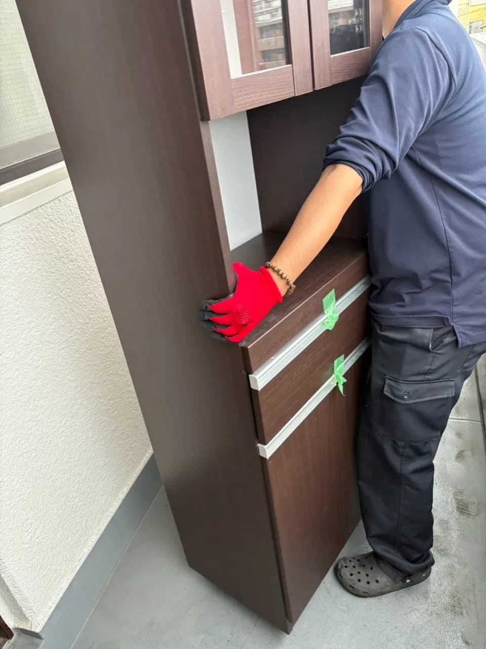 扉や引き出しをテープで留めた収納家具を扱うスタッフ