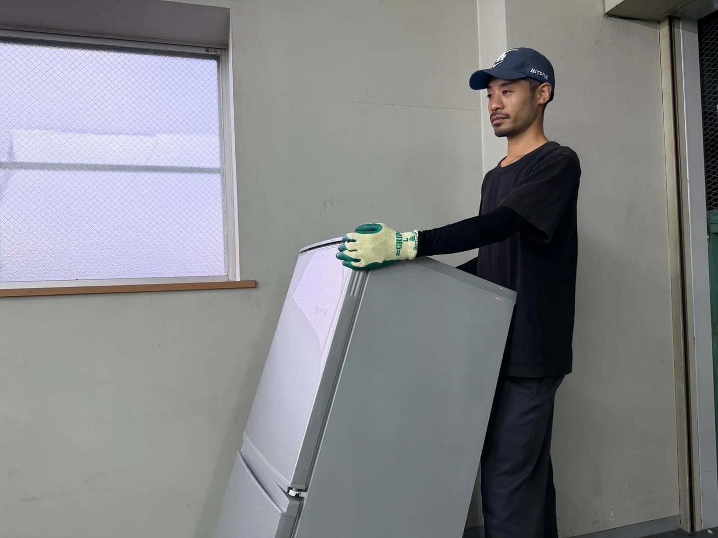 室内で冷蔵庫を支えながら運ぶアトムズのスタッフ